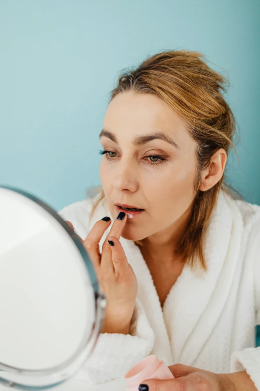 a woman putting on lipstick in front of a mirror, colour corrected, brown, line sleek, manuka