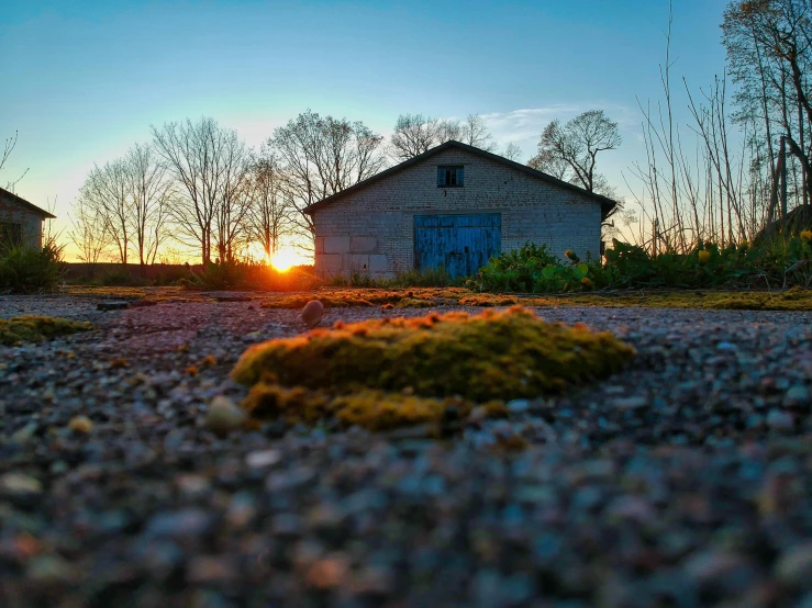 a house sitting on top of a gravel field, by Joe Stefanelli, pexels contest winner, land art, at sunrise in springtime, abandoned night hangar, low wide angle, golden hour closeup photo