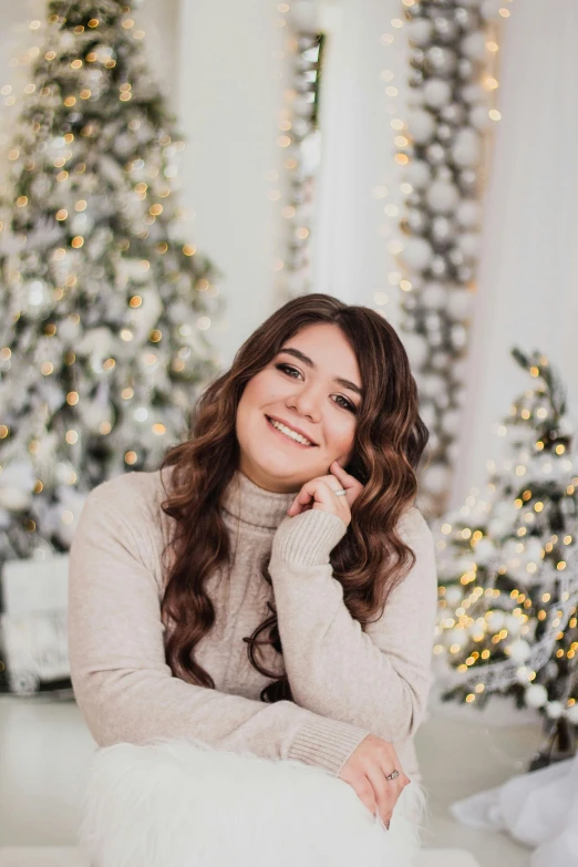 a woman sitting in front of a christmas tree, an album cover, by Julia Pishtar, trending on pexels, beautiful smile, graduation photo, brown haired, full figured