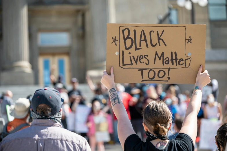 a person holding a sign that says black lives matter too, by Julia Pishtar, shutterstock, instagram post, brown, riot, albuquerque