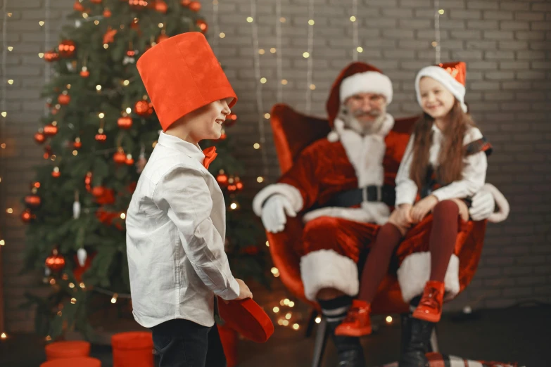 a little boy standing in front of a christmas tree, pexels contest winner, incoherents, red dress and magic witch hat, sitting on santa, 15081959 21121991 01012000 4k, top hats