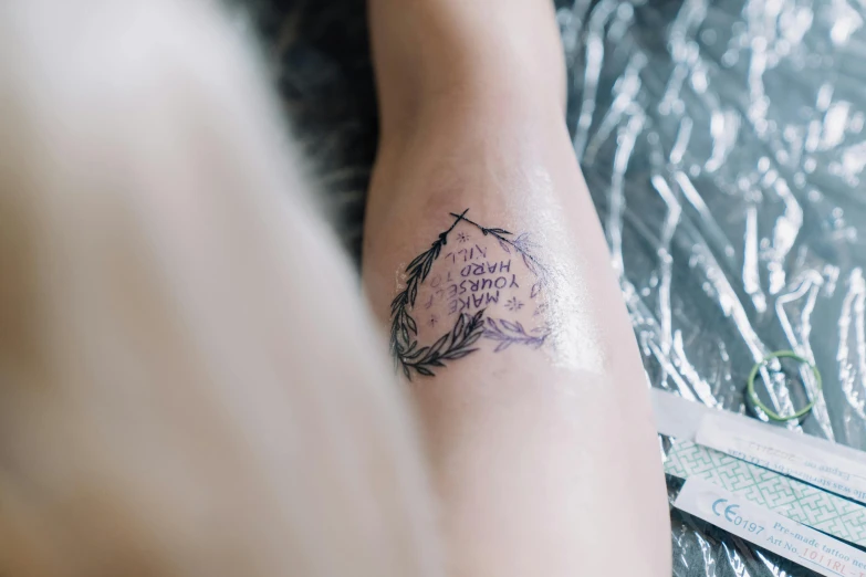 a close up of a person with a tattoo on their arm, a tattoo, trending on pexels, in laurel wreath, thigh skin, dreams are like poetry, sitting down