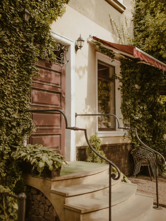 a couple of stairs going up to a building, by Emma Andijewska, pexels contest winner, art nouveau, cozy cafe background, cottage close up, low quality photo