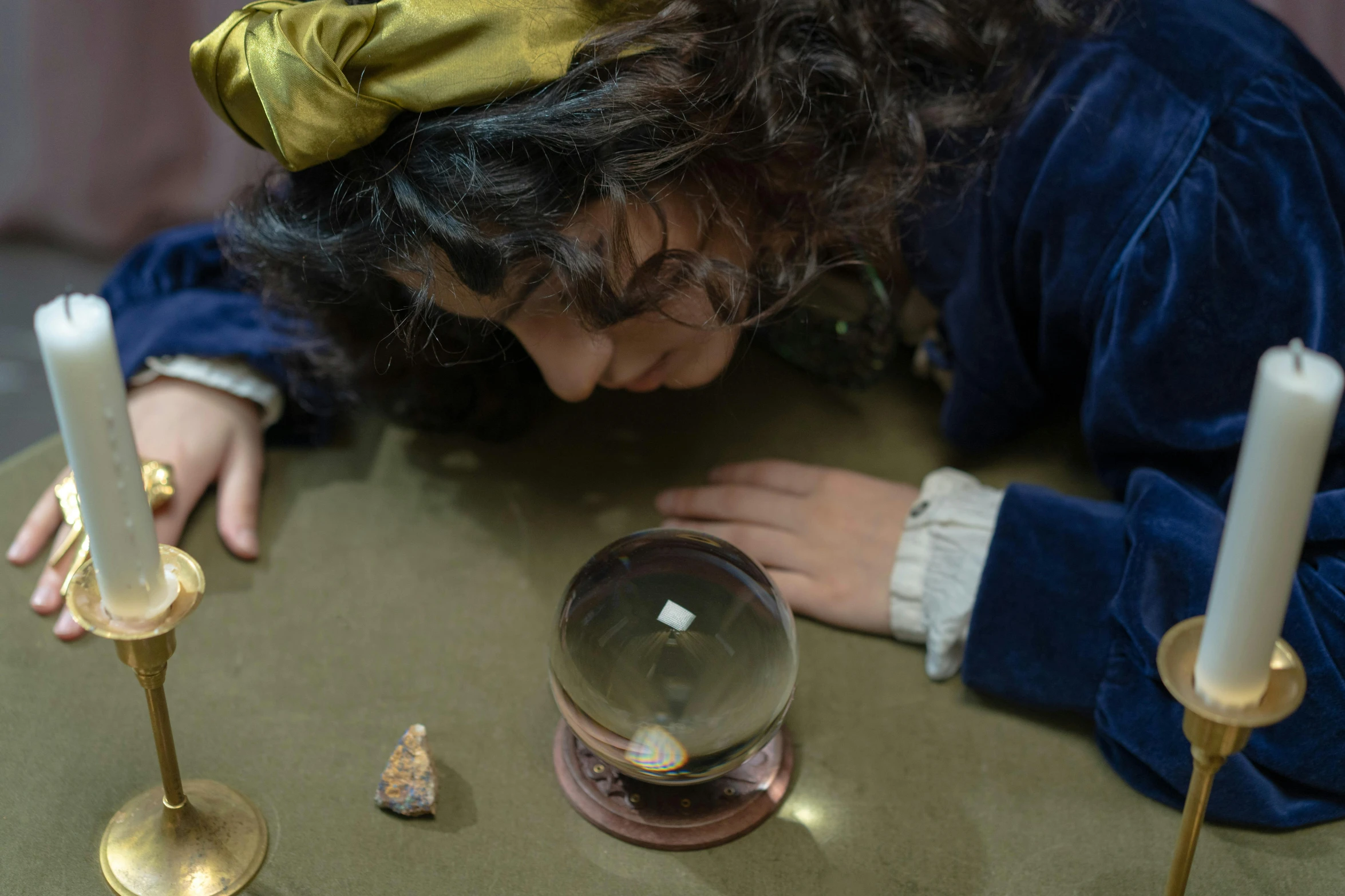 a woman looking at a crystal ball on a table, by Nathalie Rattner, 4k museum photograph, the little prince, wearing 1 8 5 0 s clothes, gold and treasure