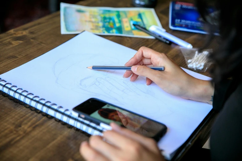 a person drawing a picture on a piece of paper, a drawing, by Julia Pishtar, trending on pexels, academic art, raphael personnaz, digitial painting, distant photo, manga drawing