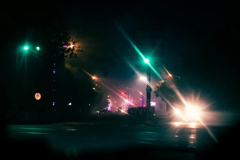 a street filled with lots of traffic at night, inspired by Elsa Bleda, unsplash, visual art, psychedelic lights and fog, street lights water refraction, dark city bus stop, purple and cyan lighting