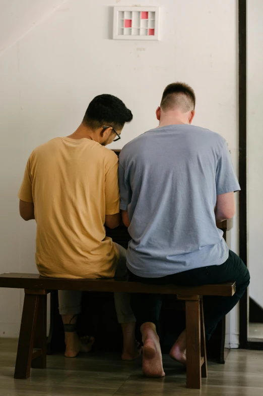 a man and a woman sitting on a bench, trending on unsplash, two men hugging, in church, thin young male, multi colored