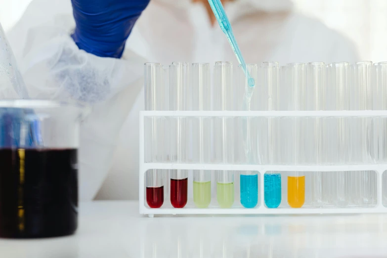 a person in a lab coat holding a tube filled with liquid, inspired by Évariste Vital Luminais, trending on pexels, brand colours are red and blue, tabletop, panels, filling with water