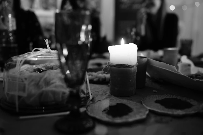 a lit candle sitting on top of a table, a black and white photo, by Caroline Mytinger, dinner is served, festive atmosphere, high details photo