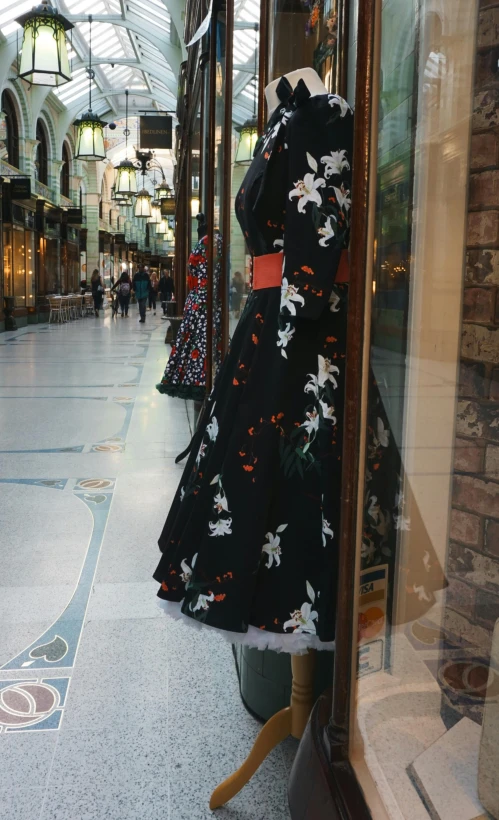 a dress on a mannequin in a store window, inspired by Modest Urgell, unsplash, arabesque, spanish alleyway, wearing a long flowery dress, woman in black robes, the dress\'s lower