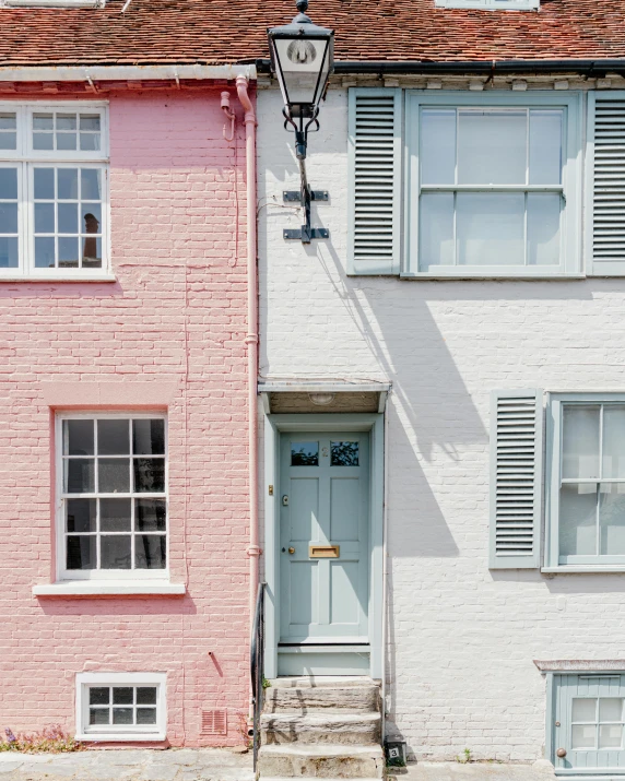 a couple of houses that are next to each other, by Rachel Reckitt, pexels contest winner, pink door, white and pale blue, lgbtq, narrow