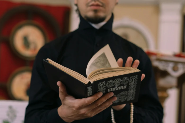 a man that is holding a book in his hands, an album cover, inspired by Mathieu Le Nain, pexels contest winner, qajar art, orthodoxy, wearing japanese techwear, reading a book, professional image