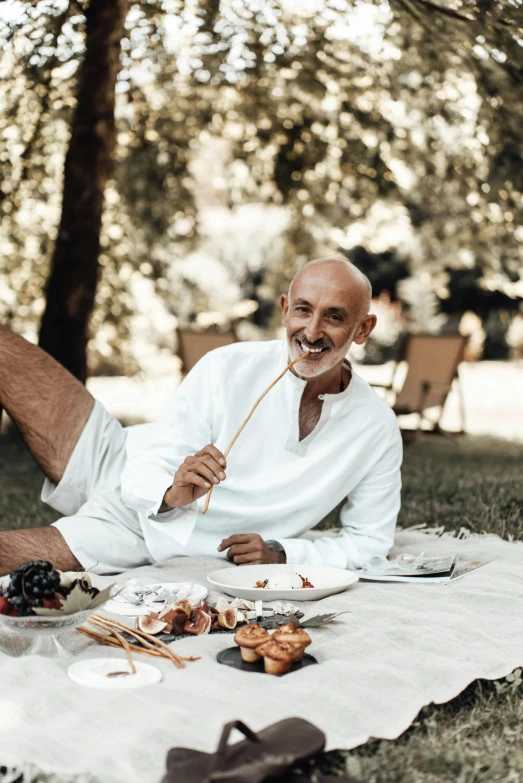 a man that is laying down on a blanket, inspired by Alberto Sughi, pexels contest winner, renaissance, people outside eating meals, wearing a white button up shirt, civ ghandi, long trunk holding a wand