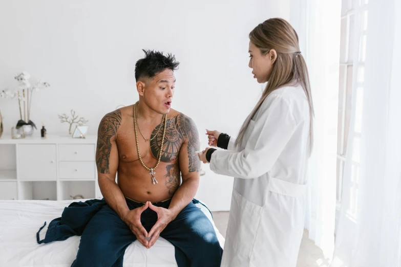 a man sitting on top of a bed next to a woman, a tattoo, pexels contest winner, male physician, damien tran, beads cross onbare chest, body swelling about to explode