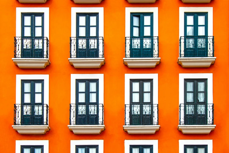 a tall building with many windows and balconies, inspired by Christo, pexels contest winner, rows of doors, spanish, vibrant orange, wall of eyes