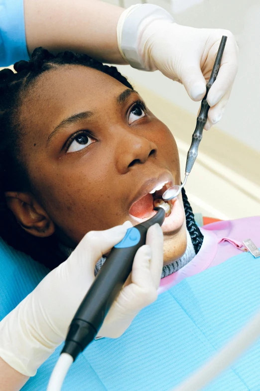 a little girl getting her teeth examined by a dentist, a digital rendering, by Ella Guru, pexels contest winner, happening, photo of a black woman, with electric arc device, uniform teeth, intricate beauty