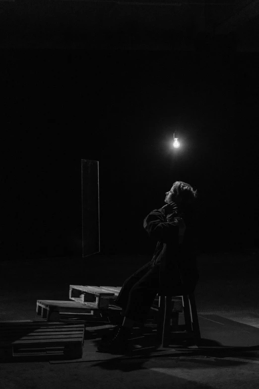 a person sitting on a chair in a dark room, a black and white photo, unsplash, park jimin, alternate album cover, search lights, longing