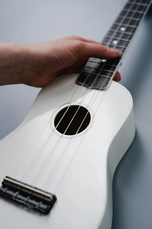 a close up of a person holding a white ukulele, by Ben Zoeller, ap, high angle shot, paul barson, tangible