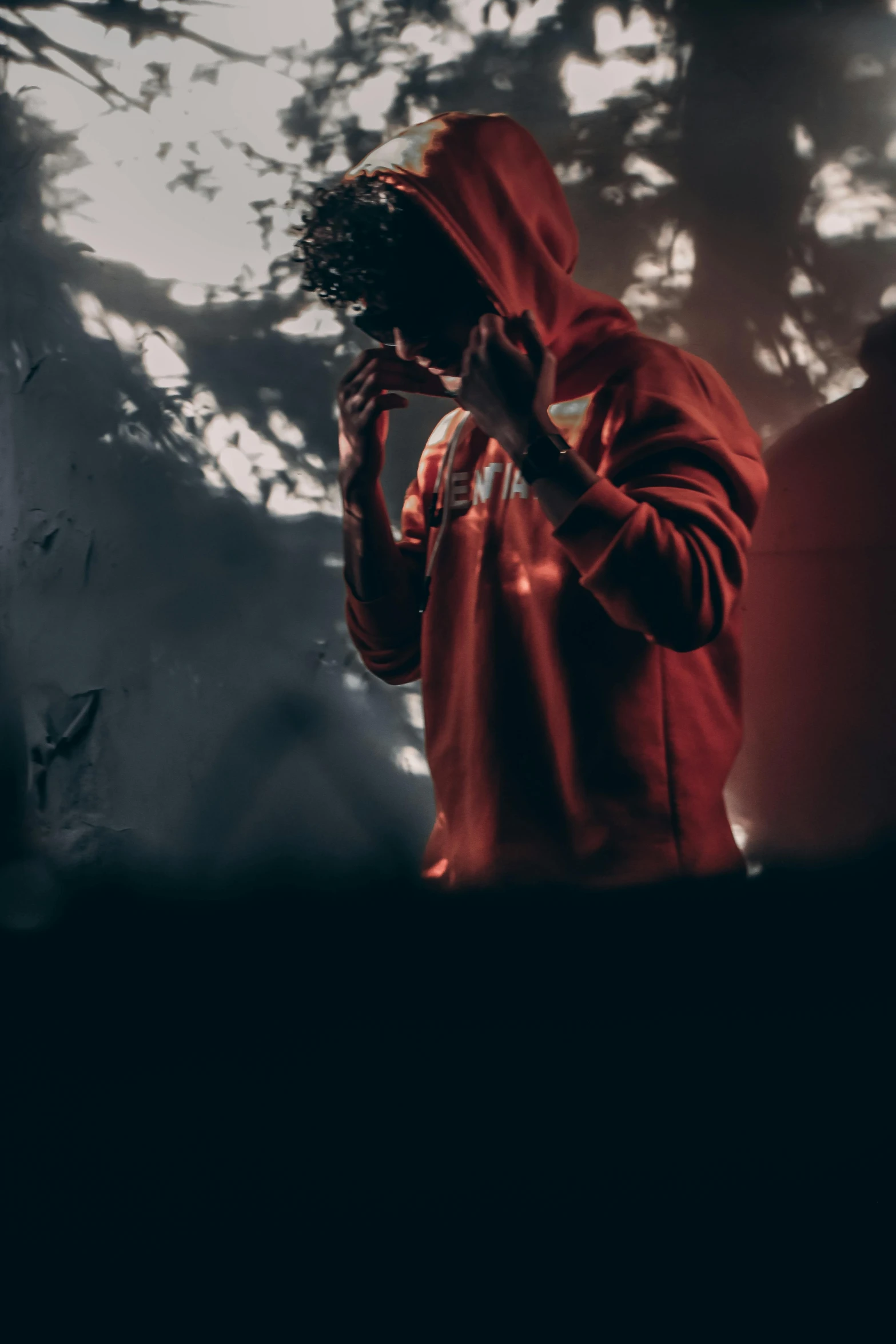 a man in a red hoodie talking on a cell phone, pexels contest winner, aestheticism, somber lighting, avatar image, ripped clothing, techwear