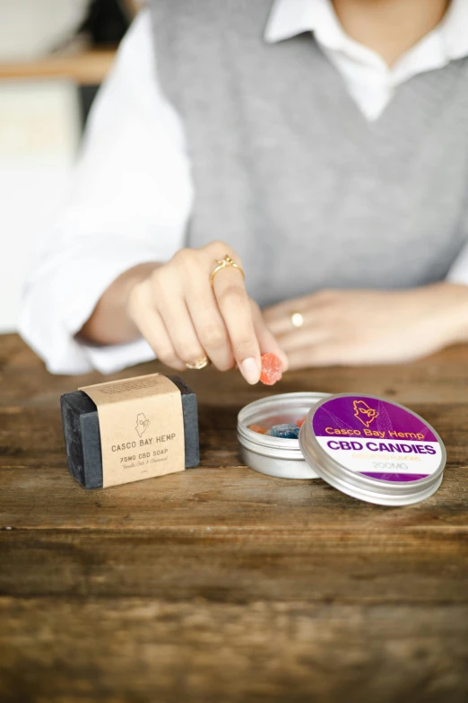 a close up of a person sitting at a table, inspired by Eden Box, 4 cannabis pots, holding a tin can, carved soap, purple