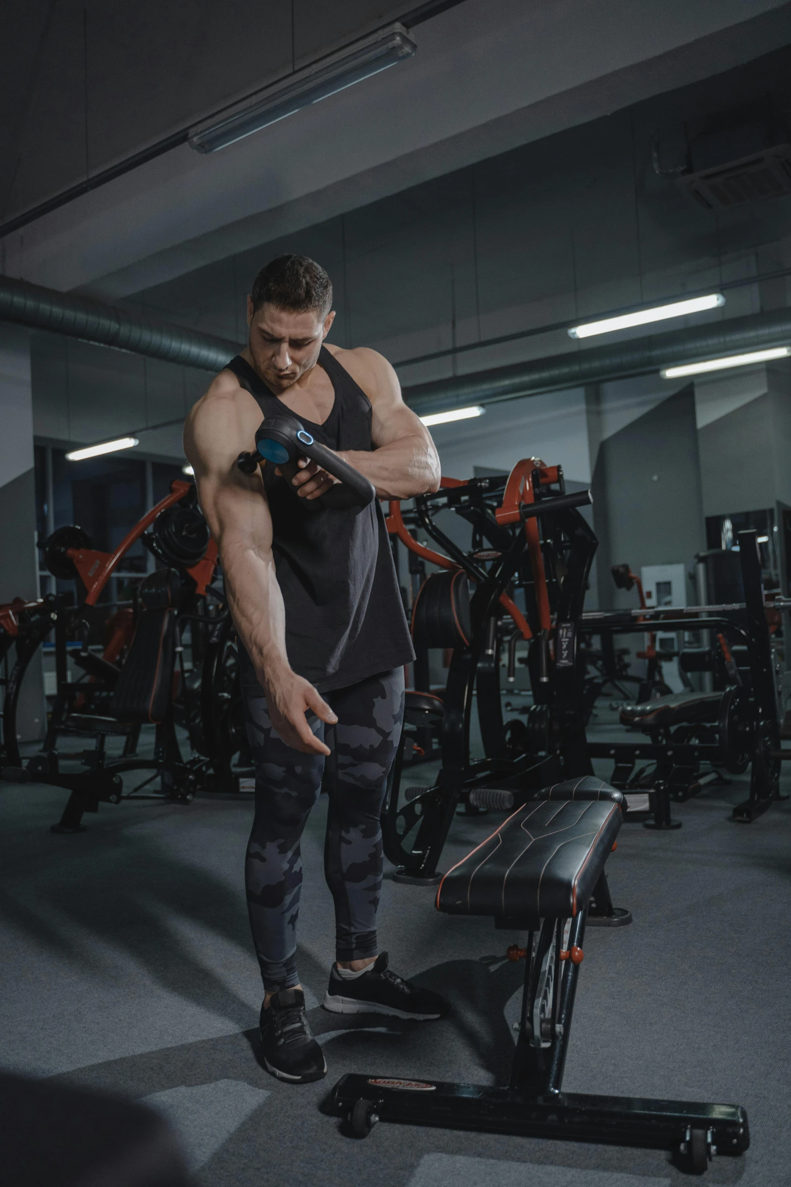a man standing next to a bench in a gym, by Adam Marczyński, ergodox, looking at his phone, using a exoskeleton, commercial