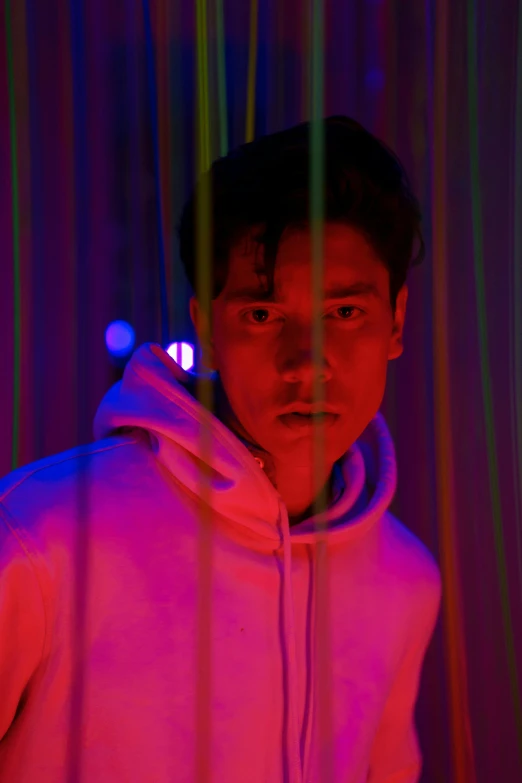 a close up of a person wearing a hoodie, by Robbie Trevino, neon background lighting, hyung tae, standing in a dimly lit room, soft calm warm neon atmosphere