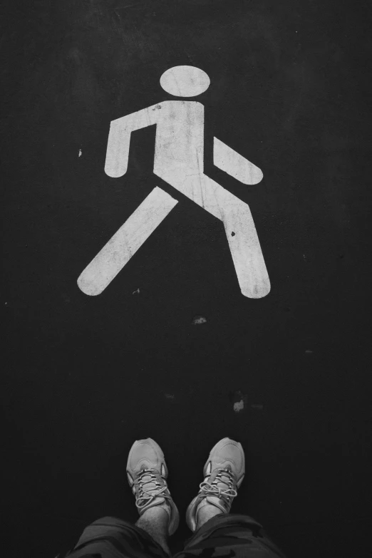 a person standing in front of a pedestrian sign, a black and white photo, unsplash, floating on space, stick figure, trampled, small legs