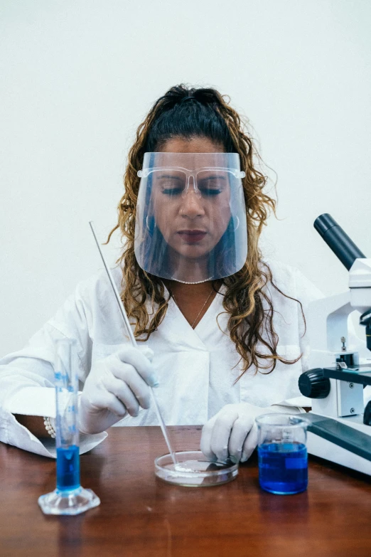 a woman sitting at a table in front of a microscope, pexels, hispanic, wearing nanotech honeycomb robe, gif, plating