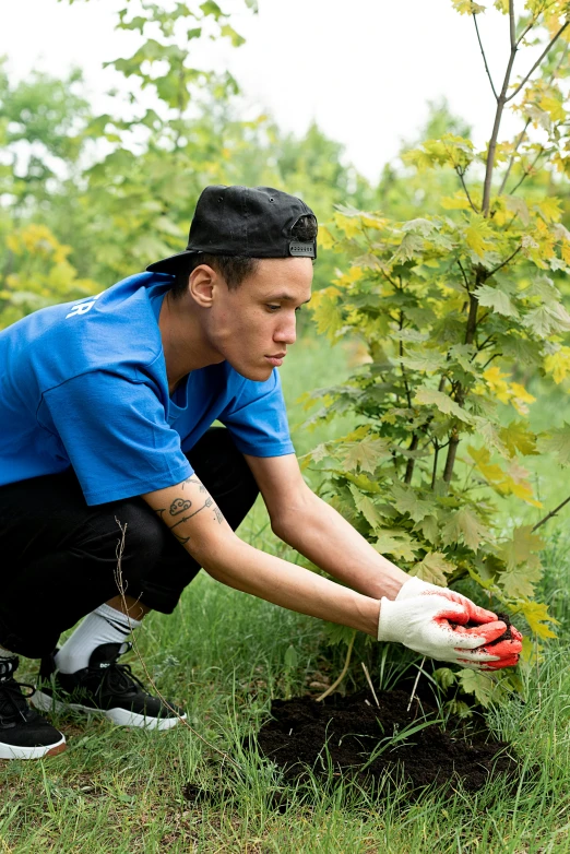 a man that is kneeling down in the grass, by Julia Pishtar, arbeitsrat für kunst, filled with plants and habitats, wearing a navy blue utility cap, 18 years old, in russia