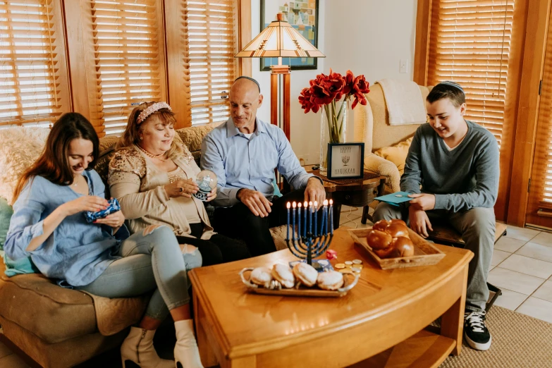 a group of people sitting on a couch in a living room, giving gifts to people, profile image, family photography, holding a candle holder