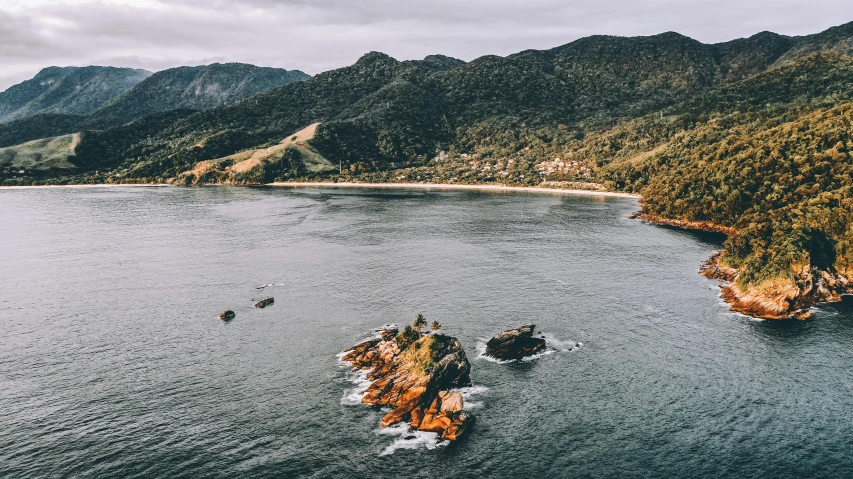 a body of water with mountains in the background, a photo, abel tasman, bird eye view, conde nast traveler photo, trees and cliffs