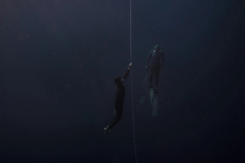a couple of people that are in the water, by Elsa Bleda, conceptual art, hanging rope, man in dark blue full body suit, denis villeneuve movie still, subsurface scandering