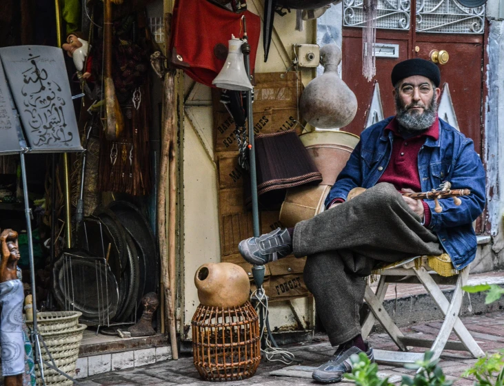 a man sitting on a bench in front of a store, pexels contest winner, qajar art, old pawn shop, full of things, jerusalem, as well as the handyboy