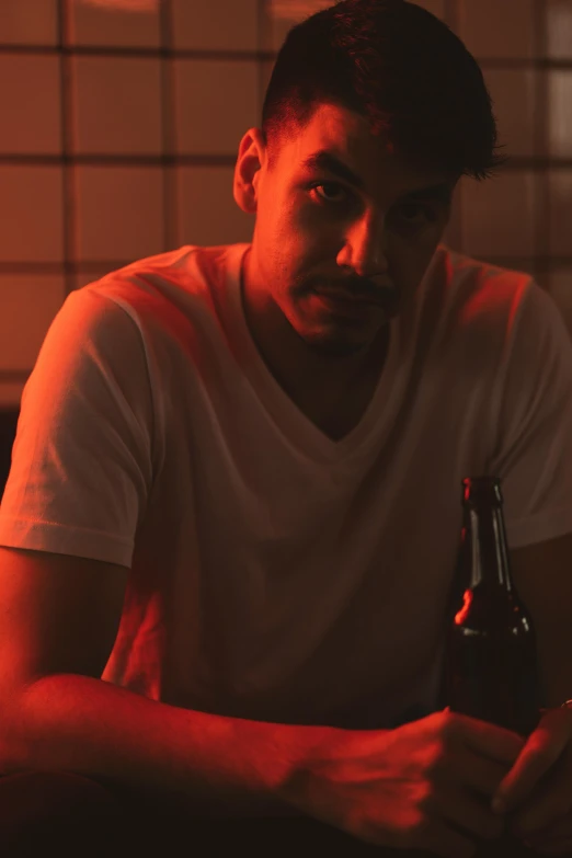 a man sitting at a table with a bottle of beer, inspired by Nan Goldin, pexels contest winner, renaissance, soft red lights, ( ( theatrical ) ), young spanish man, short stubble