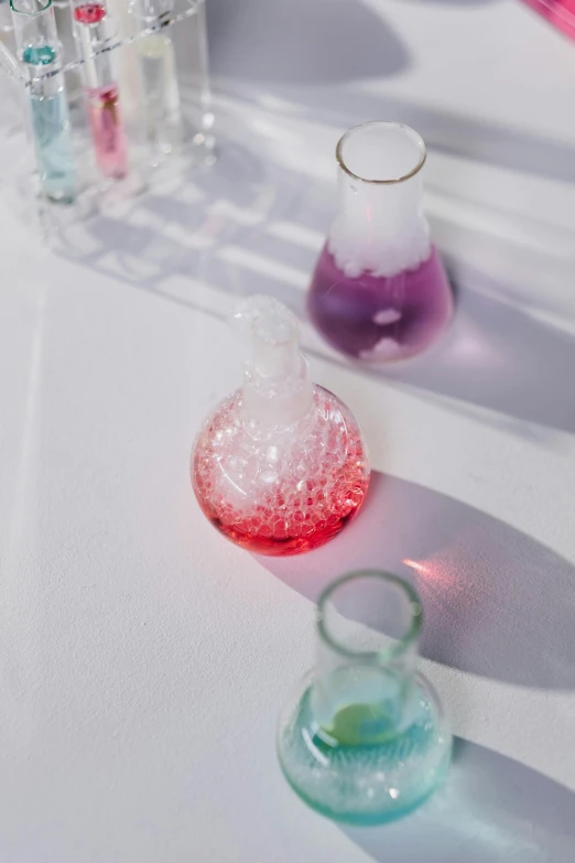 a white table topped with vases filled with liquid, unsplash, process art, chemical substances, purple and red, healthcare, klein bottle