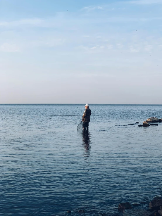 a man standing in the middle of a body of water, fishing, hammershøi, calmly conversing 8k, no cropping