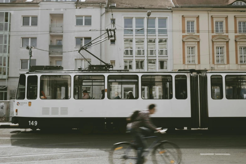 a person riding a bike in front of a train, unsplash contest winner, viennese actionism, street tram, ignant, thumbnail, white marble buildings