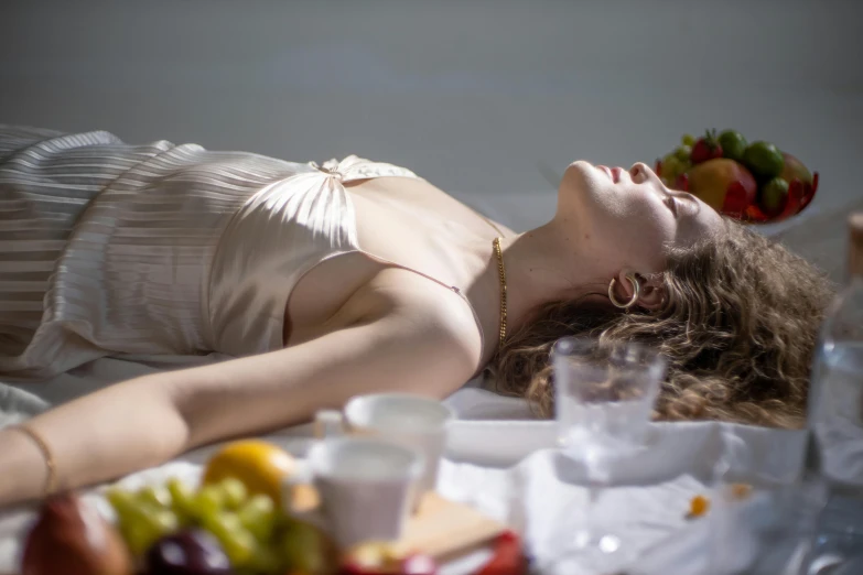 a woman laying on a bed with a plate of fruit on her head, a still life, unsplash, renaissance, sunbathed skin, backlit, ignant, porcelain pale skin