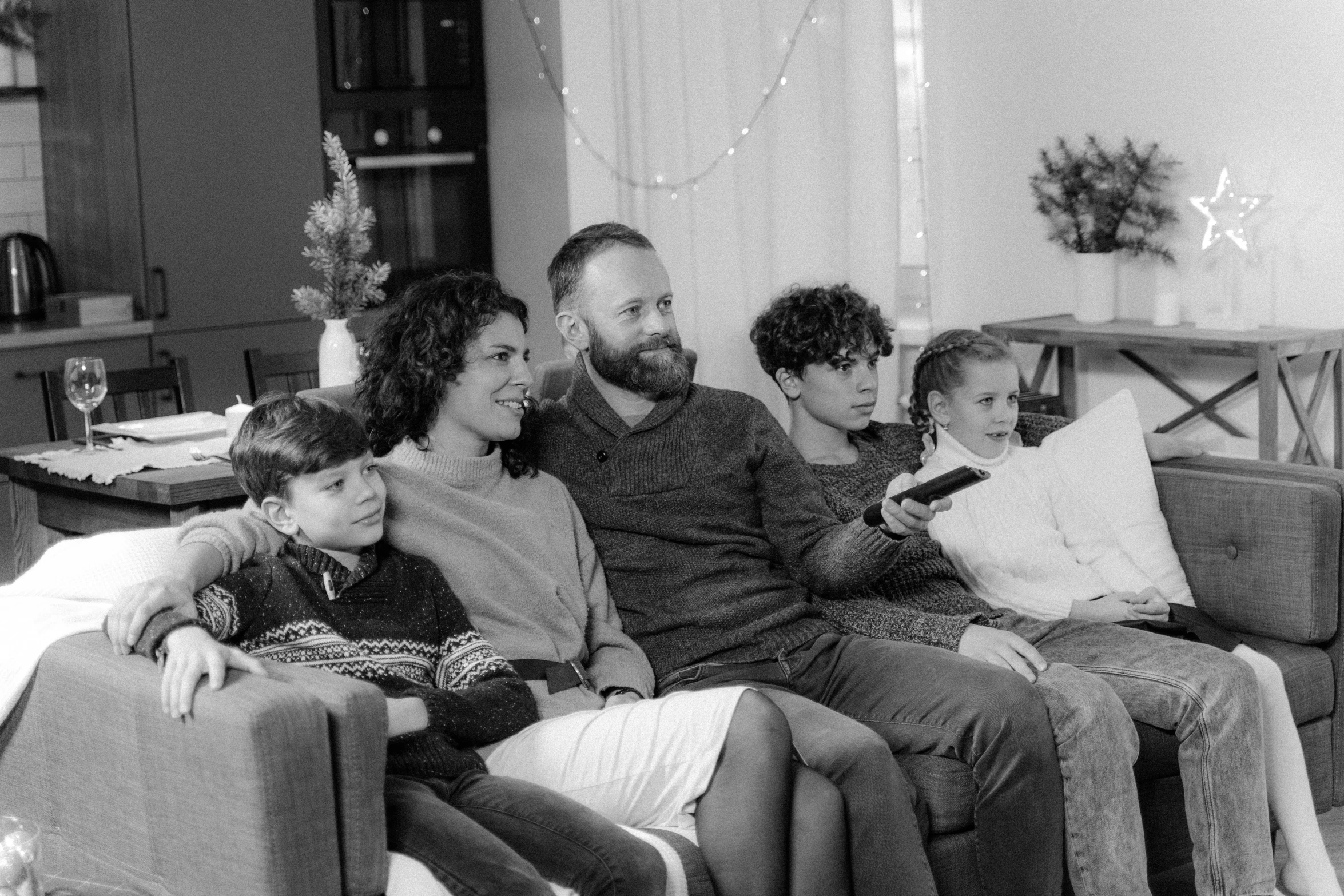 a black and white photo of a family sitting on a couch, by Carey Morris, pexels, holiday season, tv program, romanian, a handsome