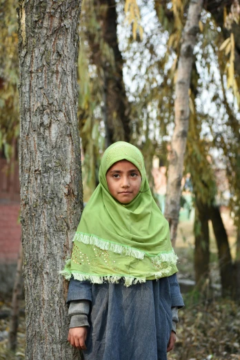 a woman standing next to a tree in a forest, hurufiyya, photo of the girl, schools, fully covered, no cropping