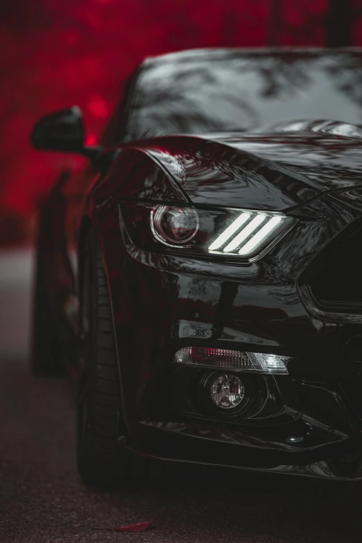 a black mustang parked in front of a red wall, pexels contest winner, car lights, dynamic closeup, gif, profile image