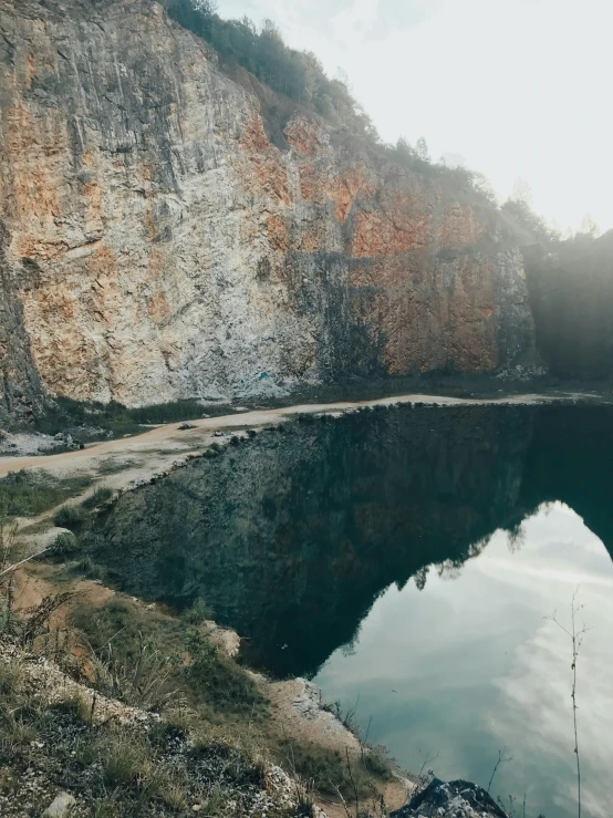 a large body of water next to a cliff, pexels contest winner, pond, limestone, low quality photo, intense look