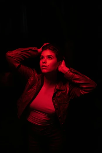 a woman standing in front of a red light, dark backdrop, looking away from the camera, brooding, multiple lights