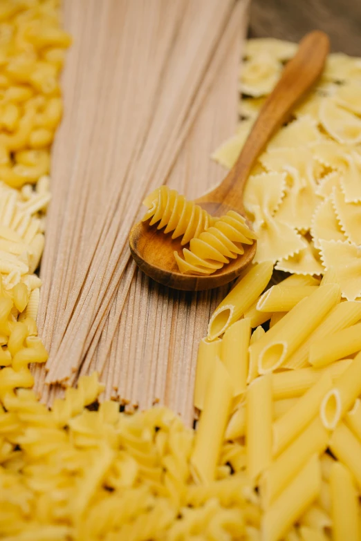 a wooden spoon sitting on top of a pile of pasta, straw, light yellow, various styles, close together