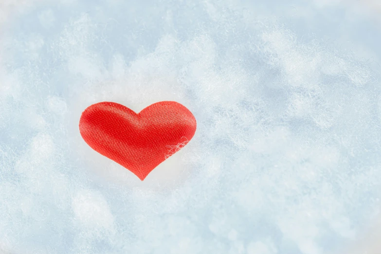 a red heart sitting on top of a snow covered ground