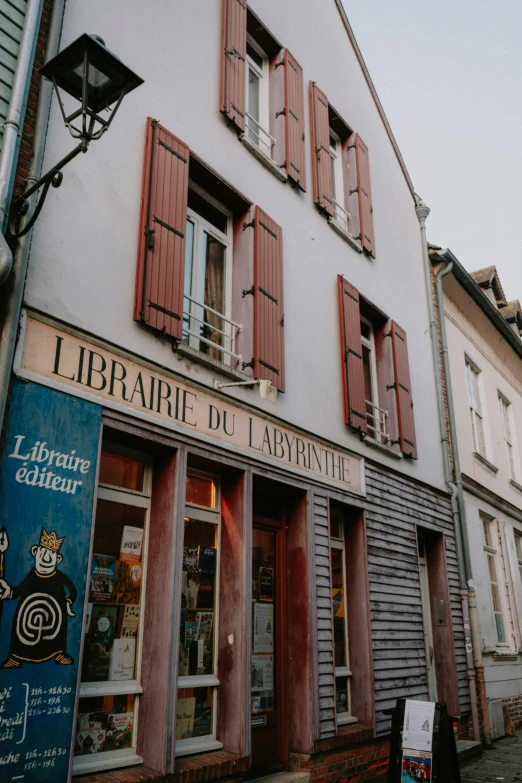 a couple of buildings that are next to each other, an album cover, by Raphaël Collin, unsplash contest winner, art nouveau, bookshops, french village exterior, small library, low quality grainy