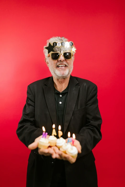 a man holding a cake with candles on it, an album cover, pexels, pop art, gray haired, implanted sunglasses, terence mckenna, studio portrait photo