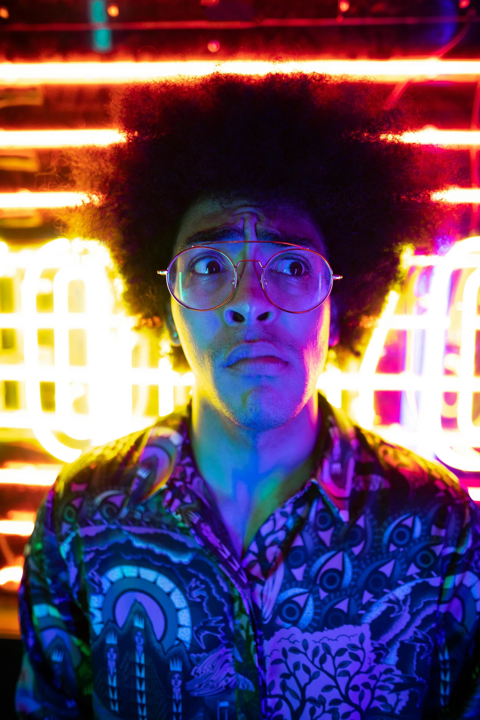 a man with an afro standing in front of neon signs, man with glasses, psychedelic lighting, lee madgwick & liam wong, looking away from viewer