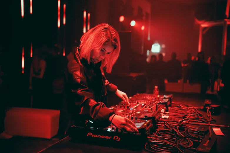 a woman that is playing some kind of music, inspired by Elsa Bleda, pexels, process art, dj at a party, small red lights, blonde, instagram post