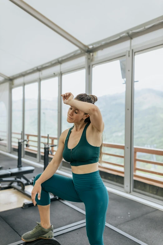 a woman standing on top of a box in a gym, by Emma Andijewska, trending on unsplash, overlooking a valley with trees, depressed dramatic bicep pose, next to window, spa